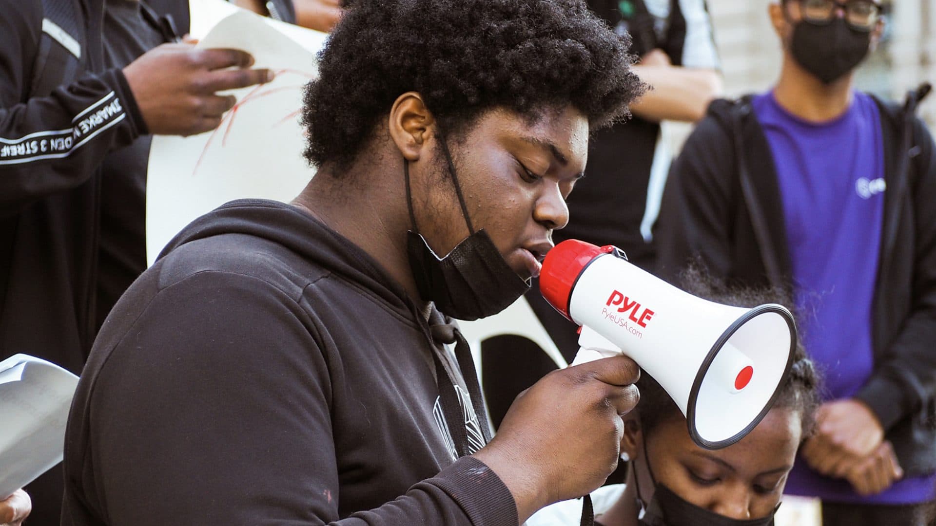 Youth Action Council member in center of image with blow horn at the rally.