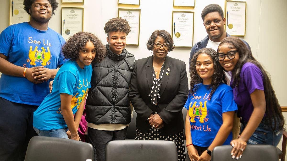 Youth Action Council members stand with Assembly Majority Leader Crystal D. Peoples-Stokes in front of a wall.