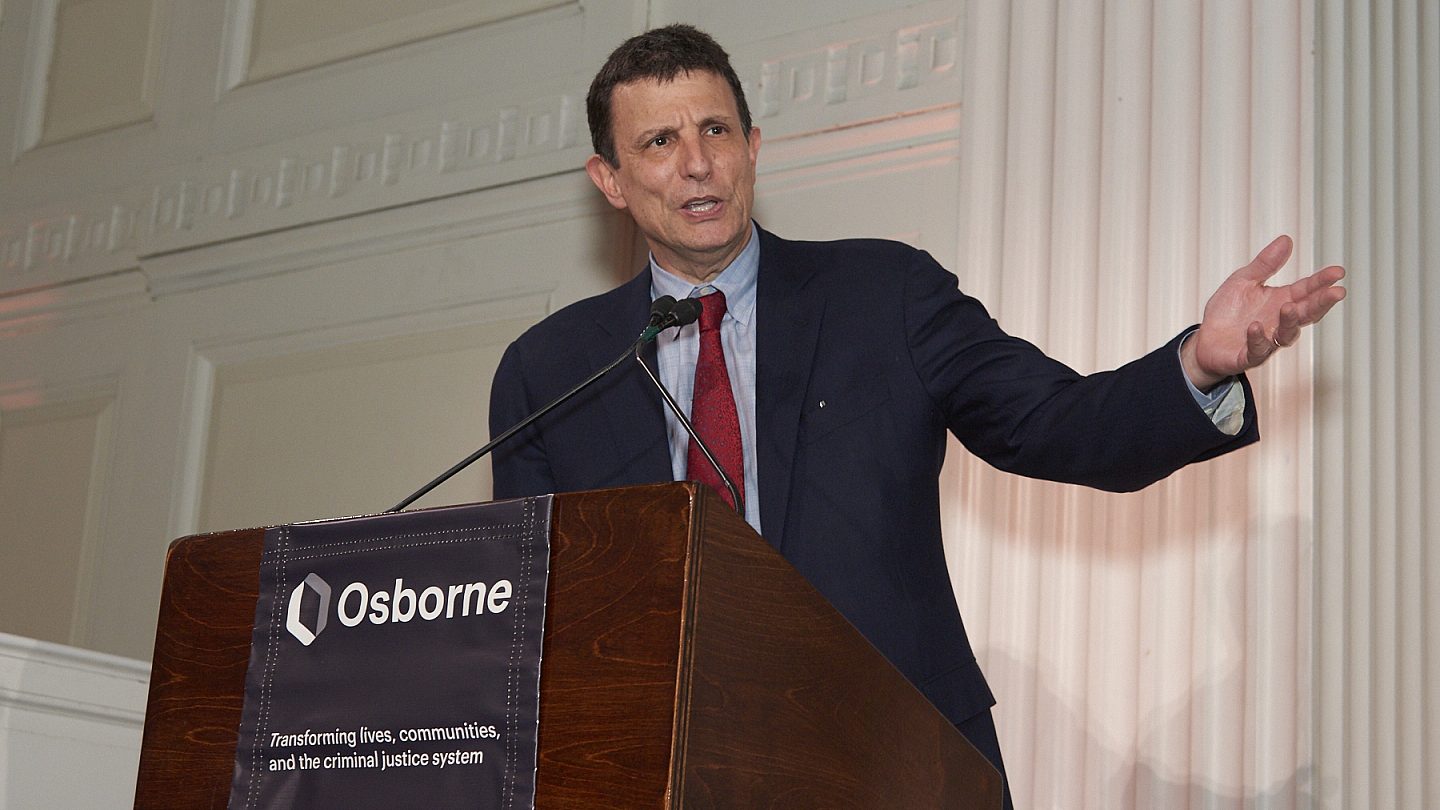 Editor David Remnick standing at the podium with his arm outstretched.