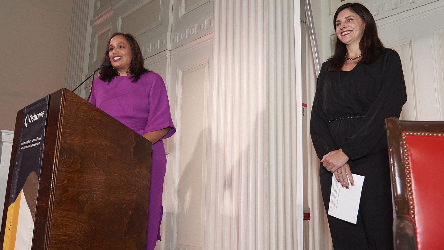 Susan Shah and Bea de la Torre of Trinity Church Wall Street standing at the podium together.