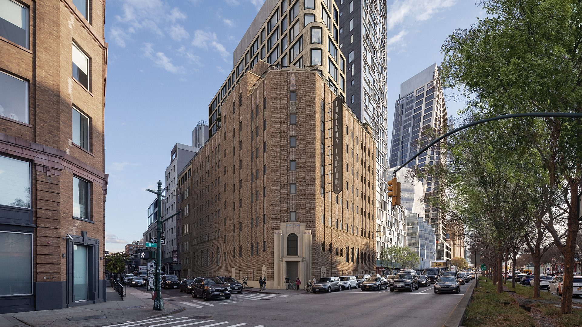 Street view of Liberty Landing. The brownish-orange building is centered with one building in foreground and two rising in the background.