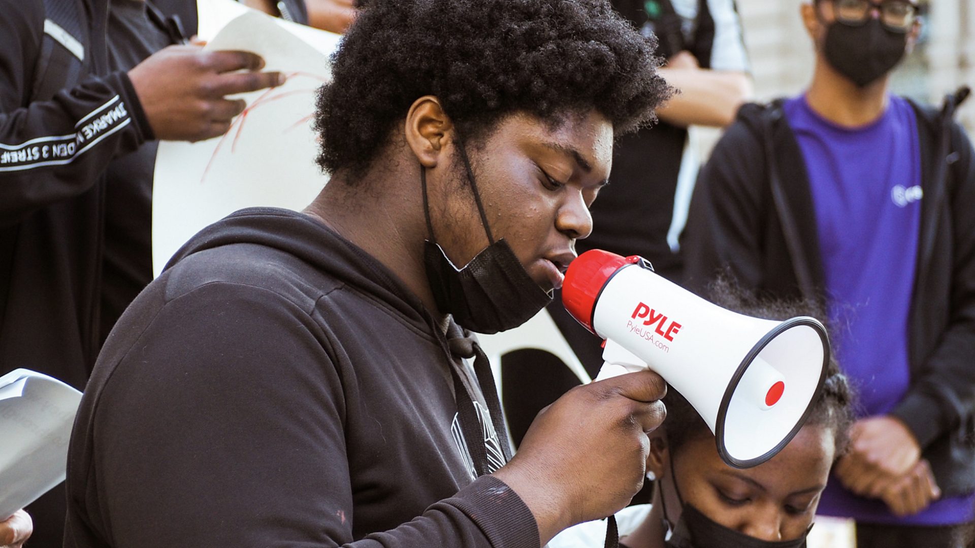 Youth Action Council member in center of image with blow horn at the rally.