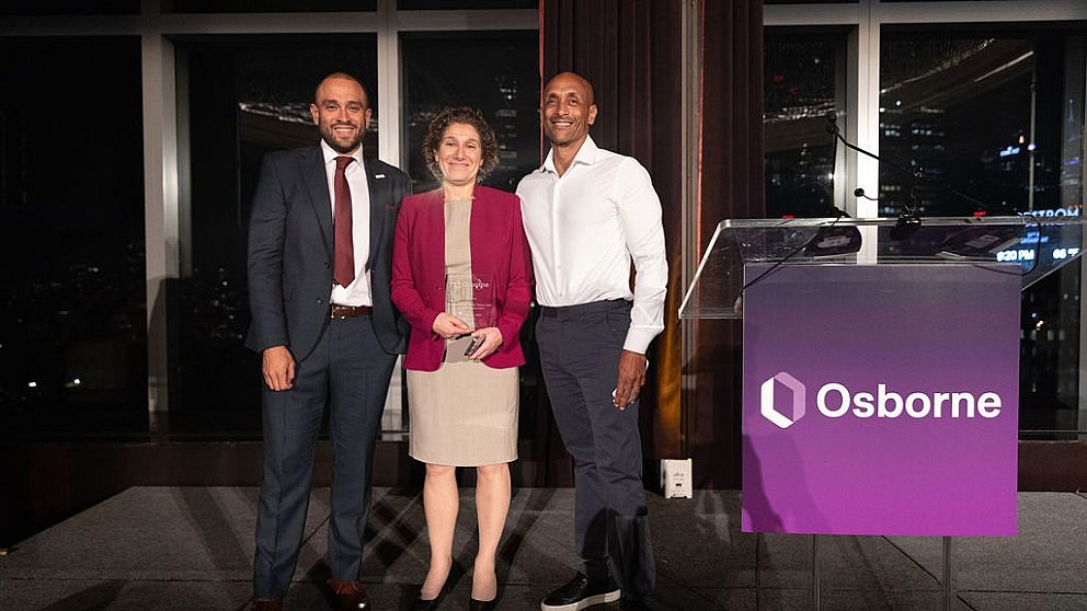 Left to right: Jonathan Monsalve stands with awardee Molly Wasow Park and Mat Wambua in front of two large windows smiling.